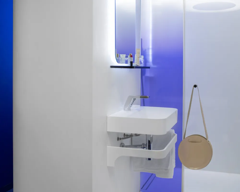 Vasque suspendue et miroir rétroéclairé sur fond bleu, hôtel capsule Paris 1er