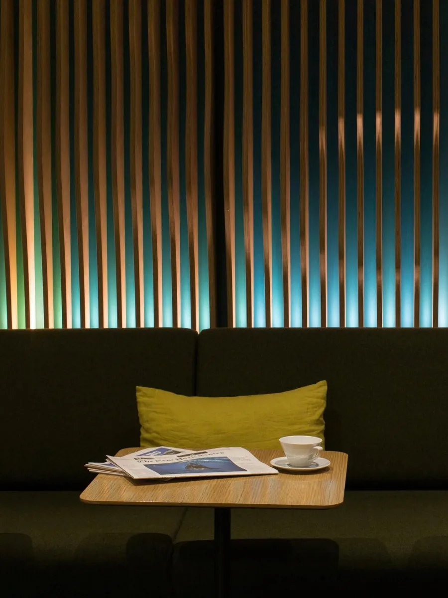 Table et coussin moutarde sous les lattes lumineuses, Green Room du boutique-hôtel Paris 1er