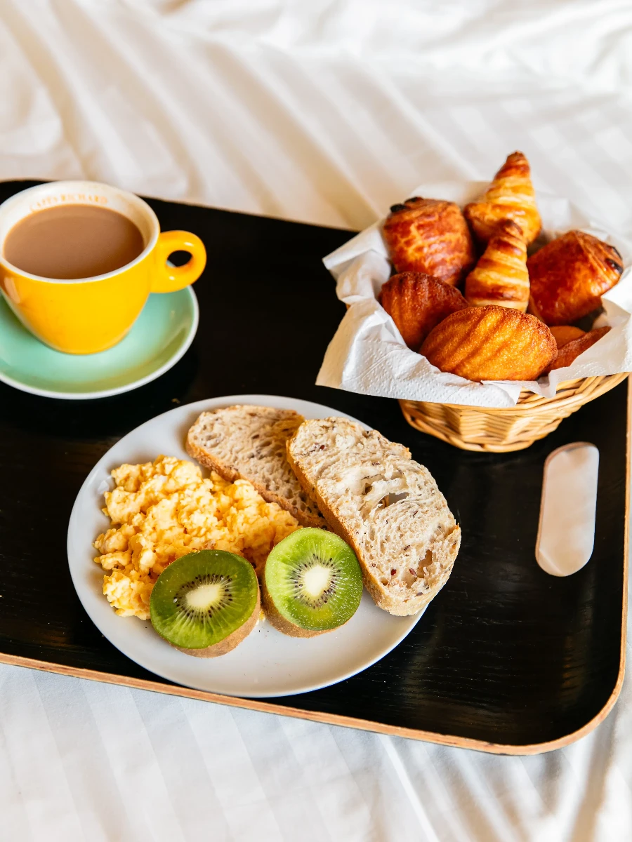 Plateau croissants, café et œufs brouillés sur le lit, hôtel design à Paris 1er