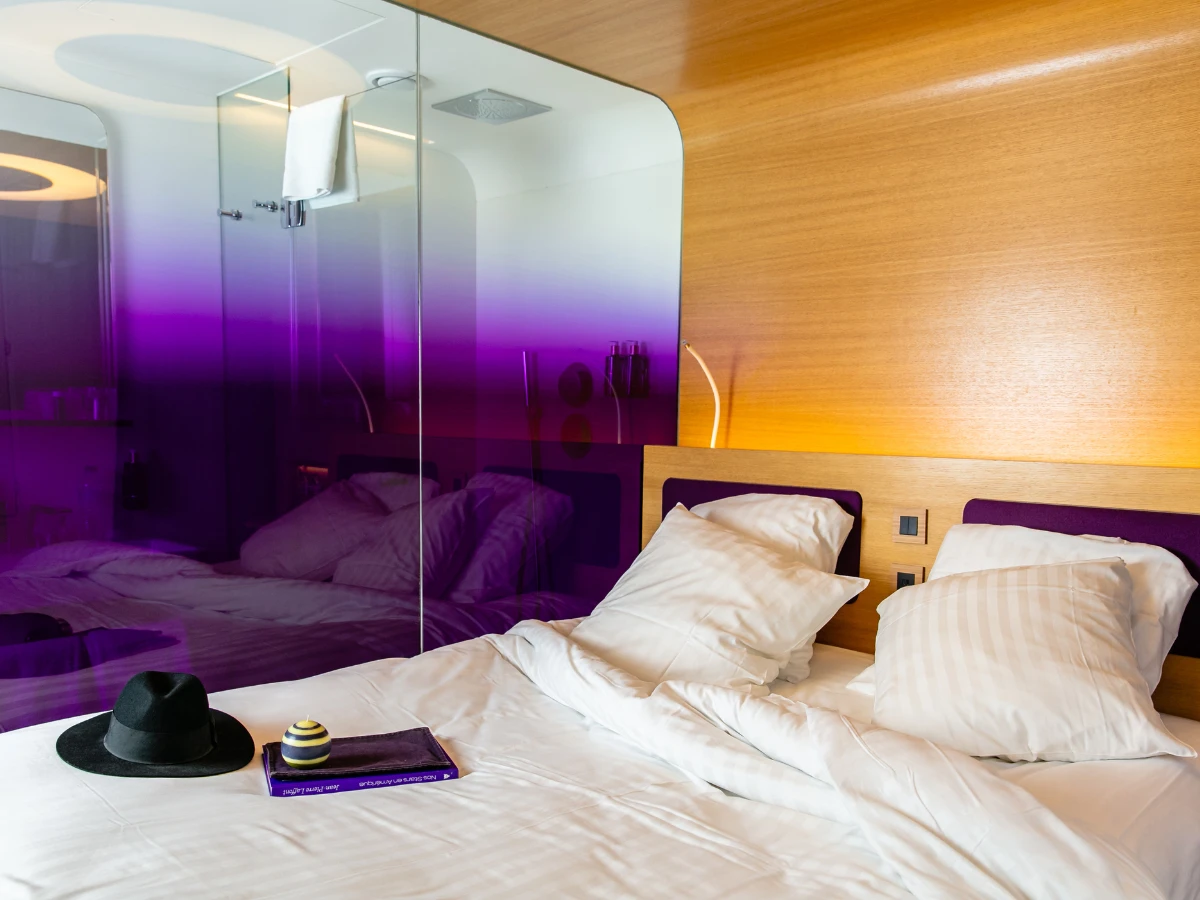 Lit double et paroi vitrée violette, chambre de l'hôtel design à Paris 1er