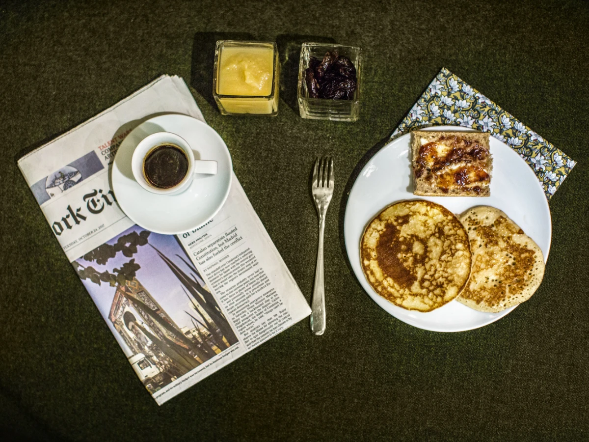 Crêpes, café et journal sur table sombre, petit-déjeuner de l'hôtel design Paris 1er