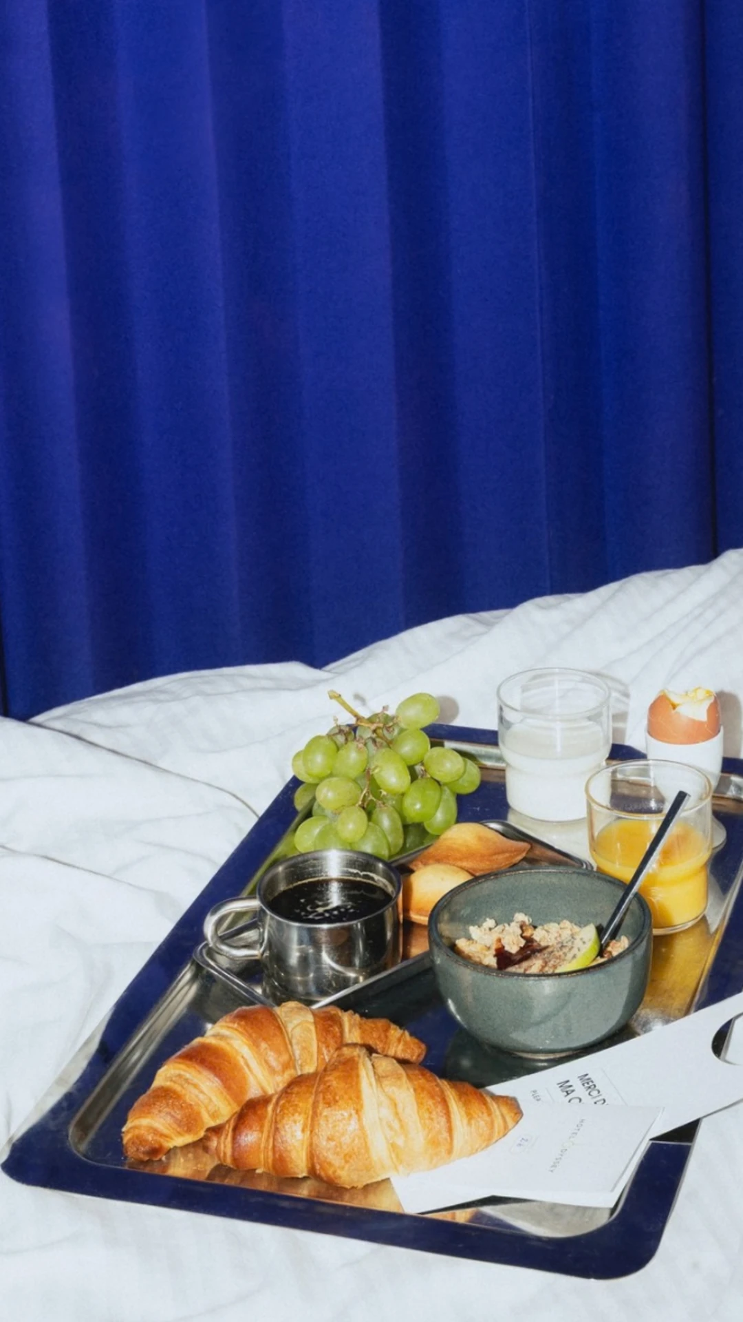 Plateau croissants et granola sur le lit, petit-déjeuner buffet de l'hôtel Paris 1er