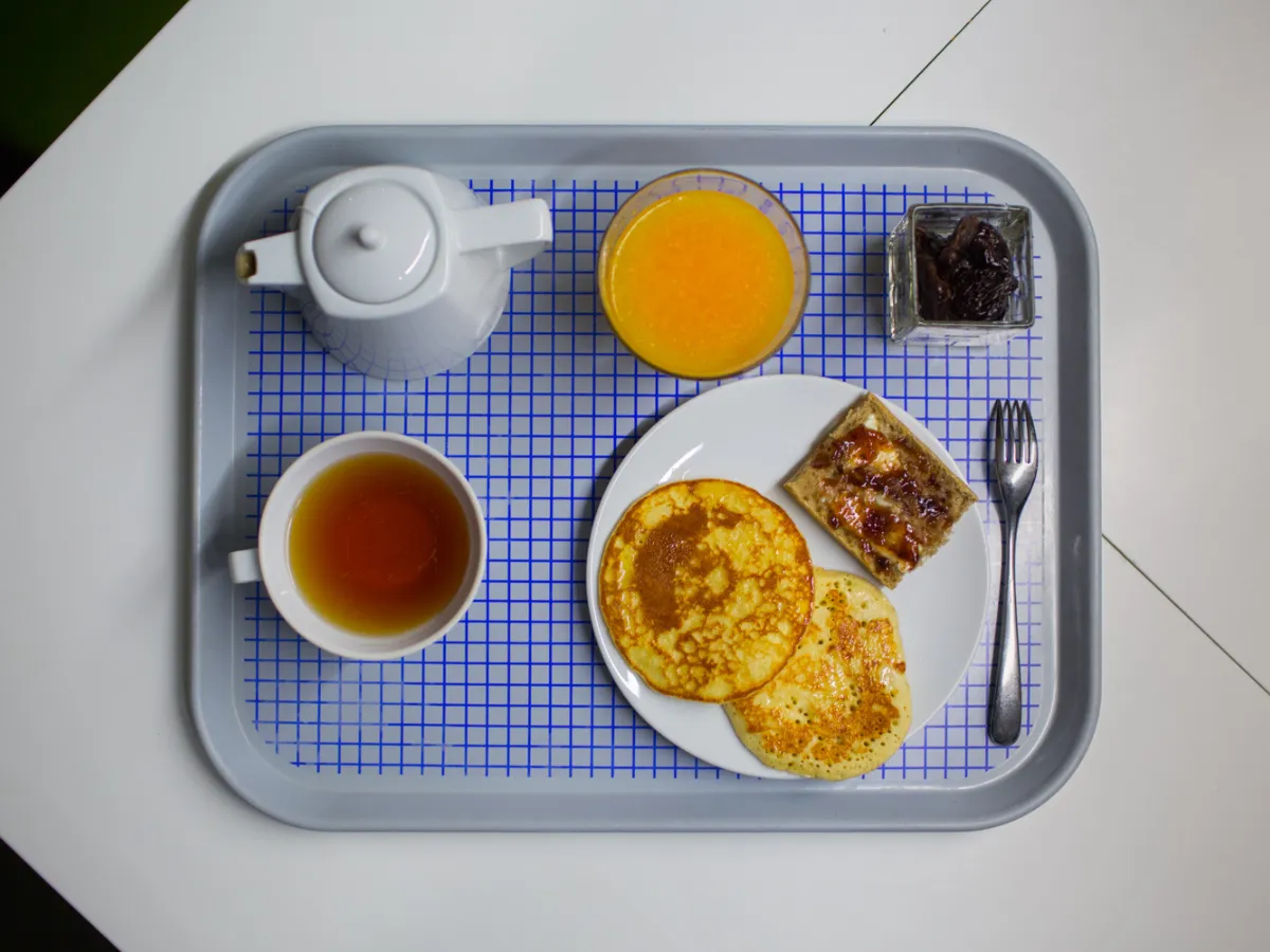 Plateau de petit-déjeuner avec pancakes, thé et jus d'orange, servi à l'hôtel design à Paris 1er