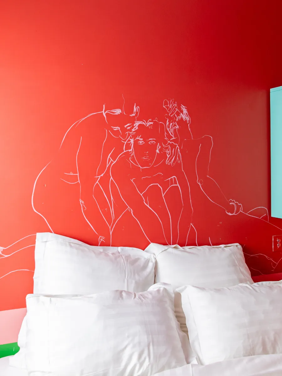Mur rouge dessiné à la main au-dessus d'un lit, signature artistique de l'Hôtel Crayon à Paris 1er