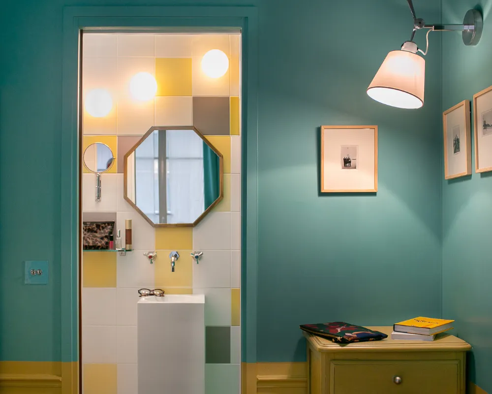 Chambre vert d'eau de l'Hôtel Crayon à Paris 1er avec salle d'eau carrelée jaune et miroir octogonal