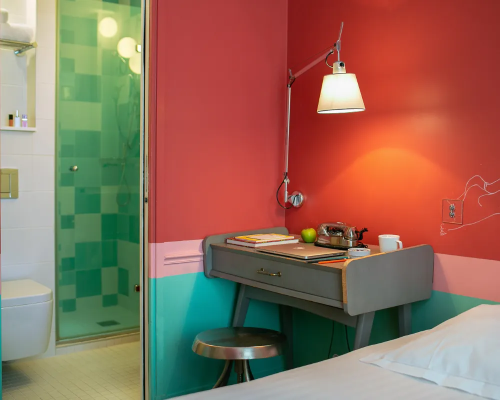 Bureau vintage gris et lampe dans une chambre rouge et turquoise de l'Hôtel Crayon, boutique-hôtel Paris 1er