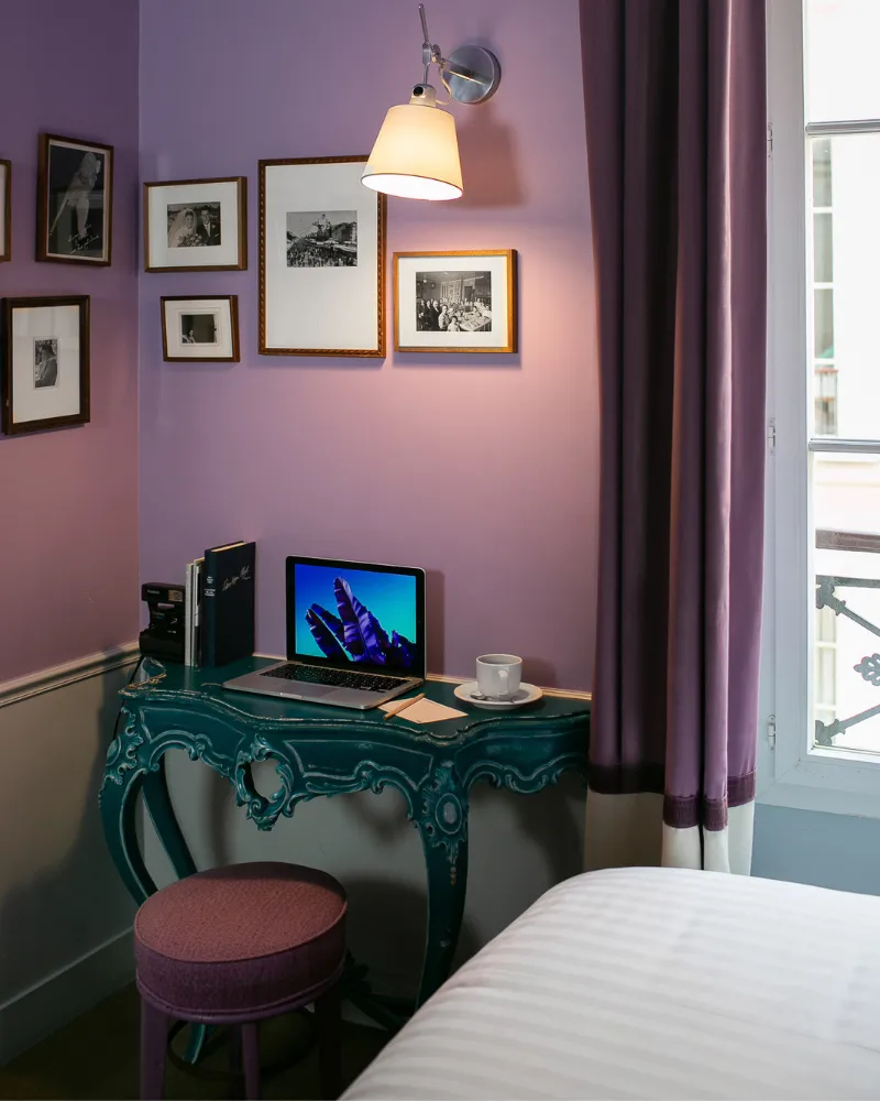 Coin bureau avec console turquoise et tabouret rose dans une chambre violette de l'Hôtel Crayon, Paris 1er