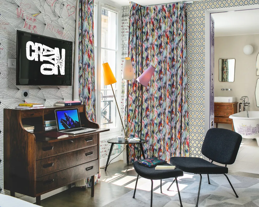 Suite Junior de l'hôtel Crayon, Paris 1er : secrétaire vintage, fauteuils et salle de bain ouverte, près du Louvre
