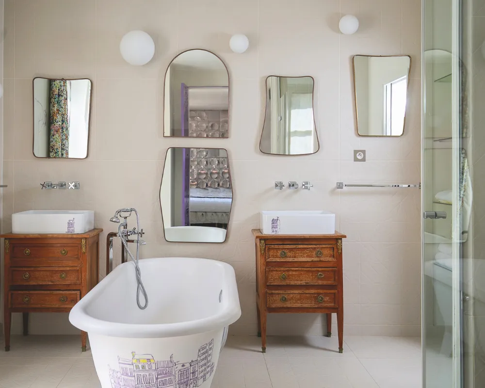 Salle de bain de la Suite Junior de l'Hôtel Crayon à Paris 1er : baignoire, deux vasques sur commodes vintage et miroirs