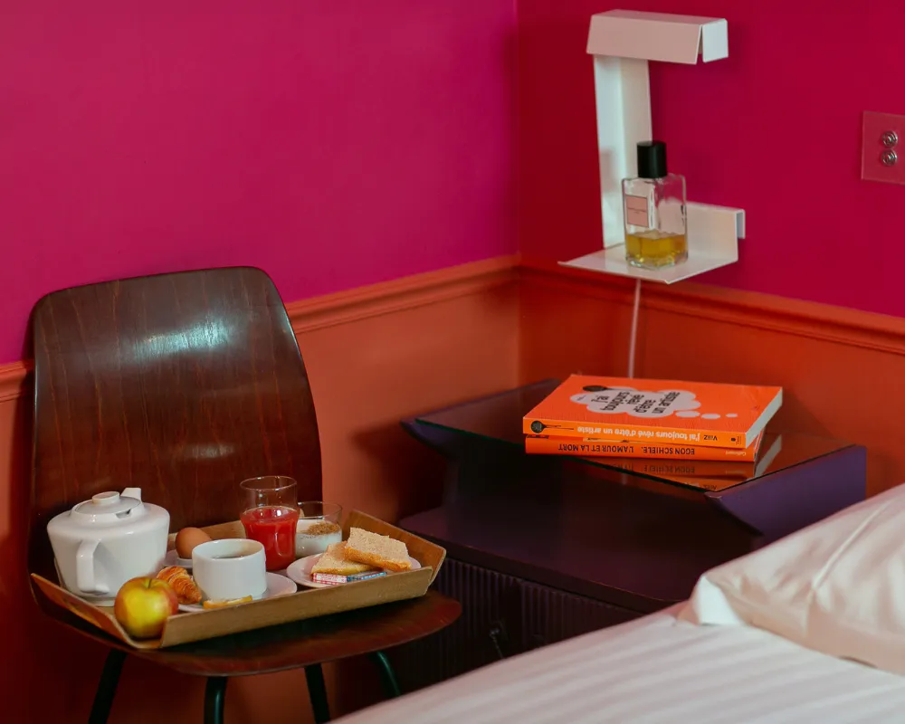 Petit-déjeuner servi en chambre sur un plateau dans une chambre rose fuchsia de l'Hôtel Crayon à Paris 1er