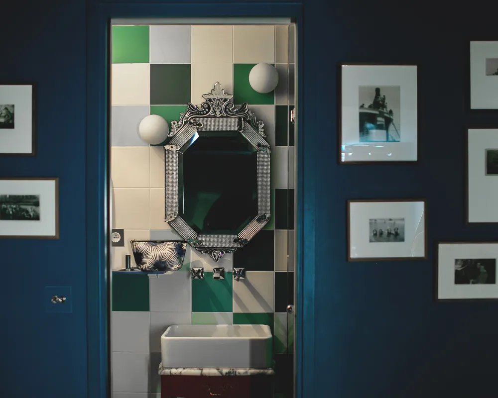 Salle de bain carrelée vert et blanc avec miroir vénitien, vue depuis une chambre bleu nuit de l'Hôtel Crayon à Paris 1er