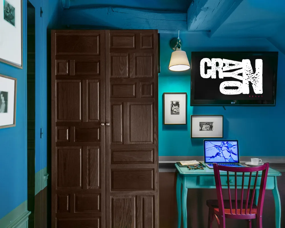 Chambre bleue de l'Hôtel Crayon à Paris 1er : porte ancienne en bois, bureau turquoise et chaise rose