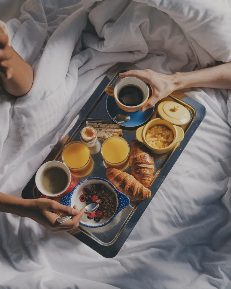 Plateau de petit-déjeuner avec croissants, jus d'orange et café servi au lit à l'Hôtel Crayon, Paris 1er