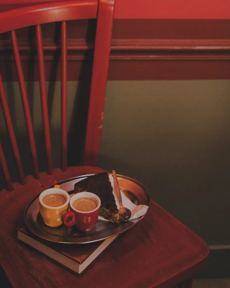 Plateau de café et thé posé sur une chaise rouge en bois dans une chambre de l'Hôtel Crayon, Paris 1er