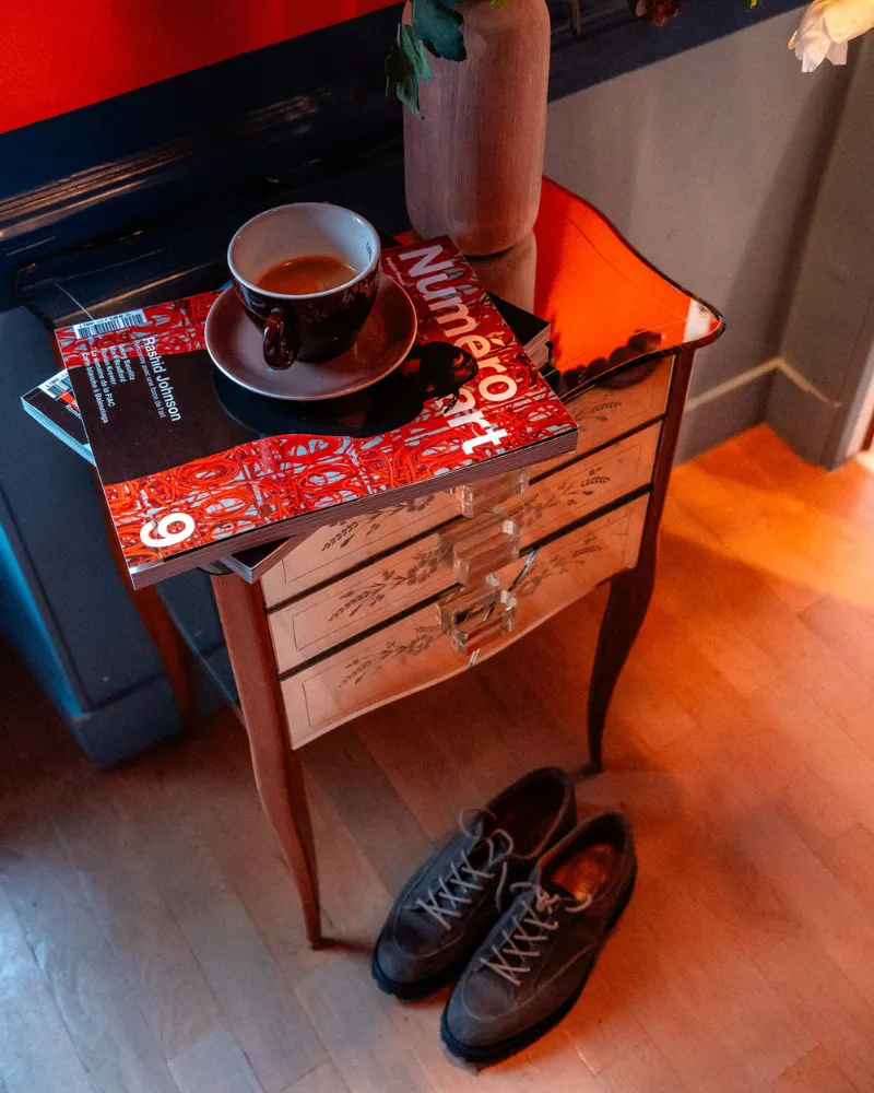 Table de chevet vintage peinte en rouge avec tasse de thé dans une chambre de l'Hôtel Crayon à Paris 1er