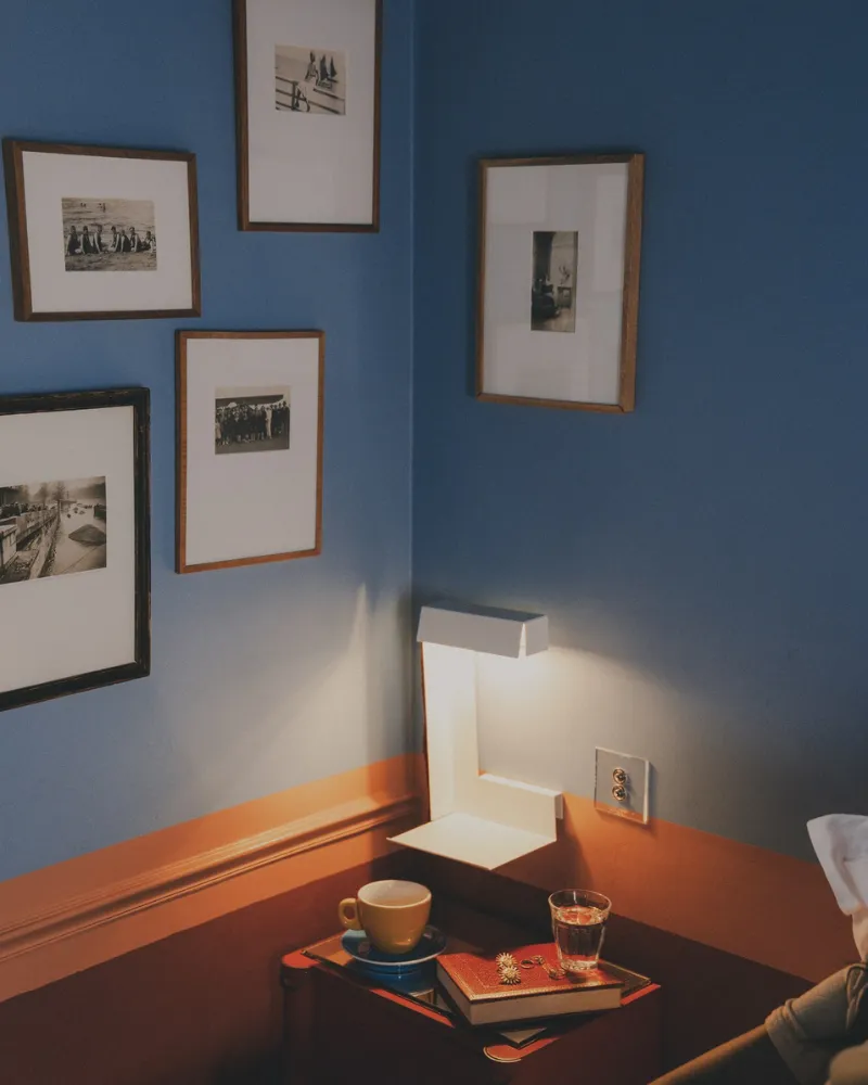 Chambre bleue de l'Hôtel Crayon à Paris 1er avec galerie de photos encadrées et chevet éclairé