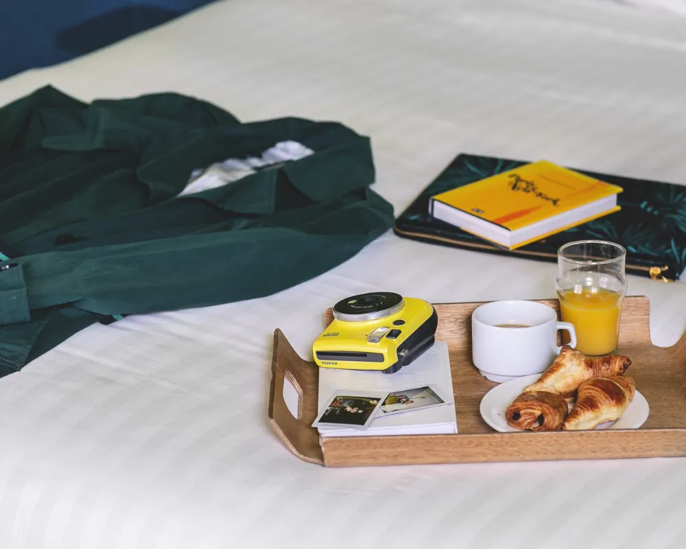 Petit-déjeuner continental sur le lit avec appareil photo jaune et livre, Chambre Insolite Double de l'Hôtel Crayon, Paris