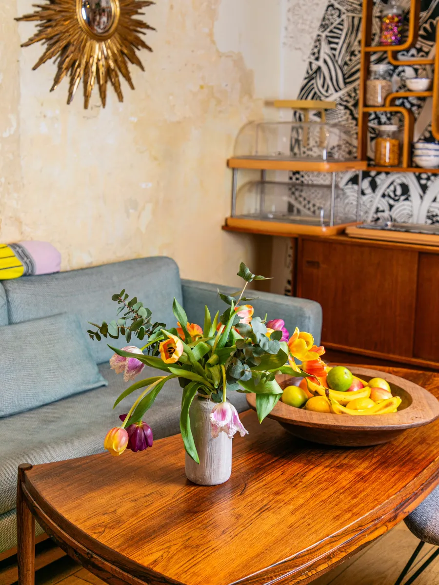 Honesty Bar de l'Hôtel Crayon à Paris 1er : salon vintage avec canapé, fleurs et corbeille de fruits