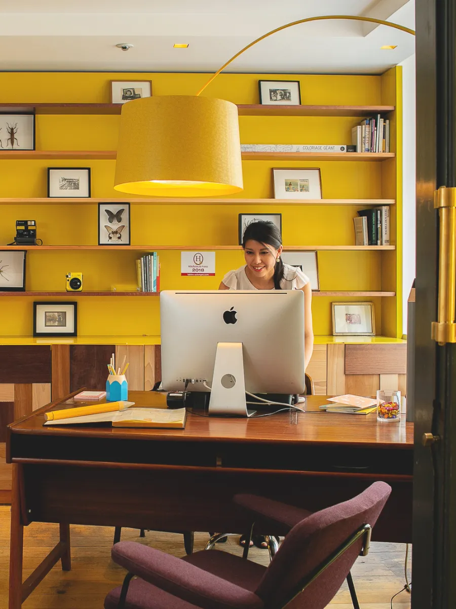 Accueil 24h/24 à la réception de l'Hôtel Crayon, Paris 1er, avec bibliothèque jaune et bureau vintage