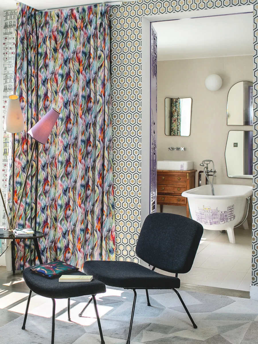 Suite Junior avec bain de l'Hôtel Crayon à Paris 1er : fauteuils noirs, rideaux colorés et baignoire sur pieds en fond