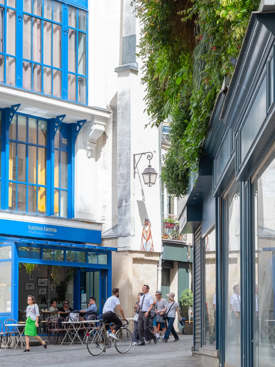 Lively street with a blue-fronted café and terrace in the Les Halles district, near the Hôtel Crayon in Paris