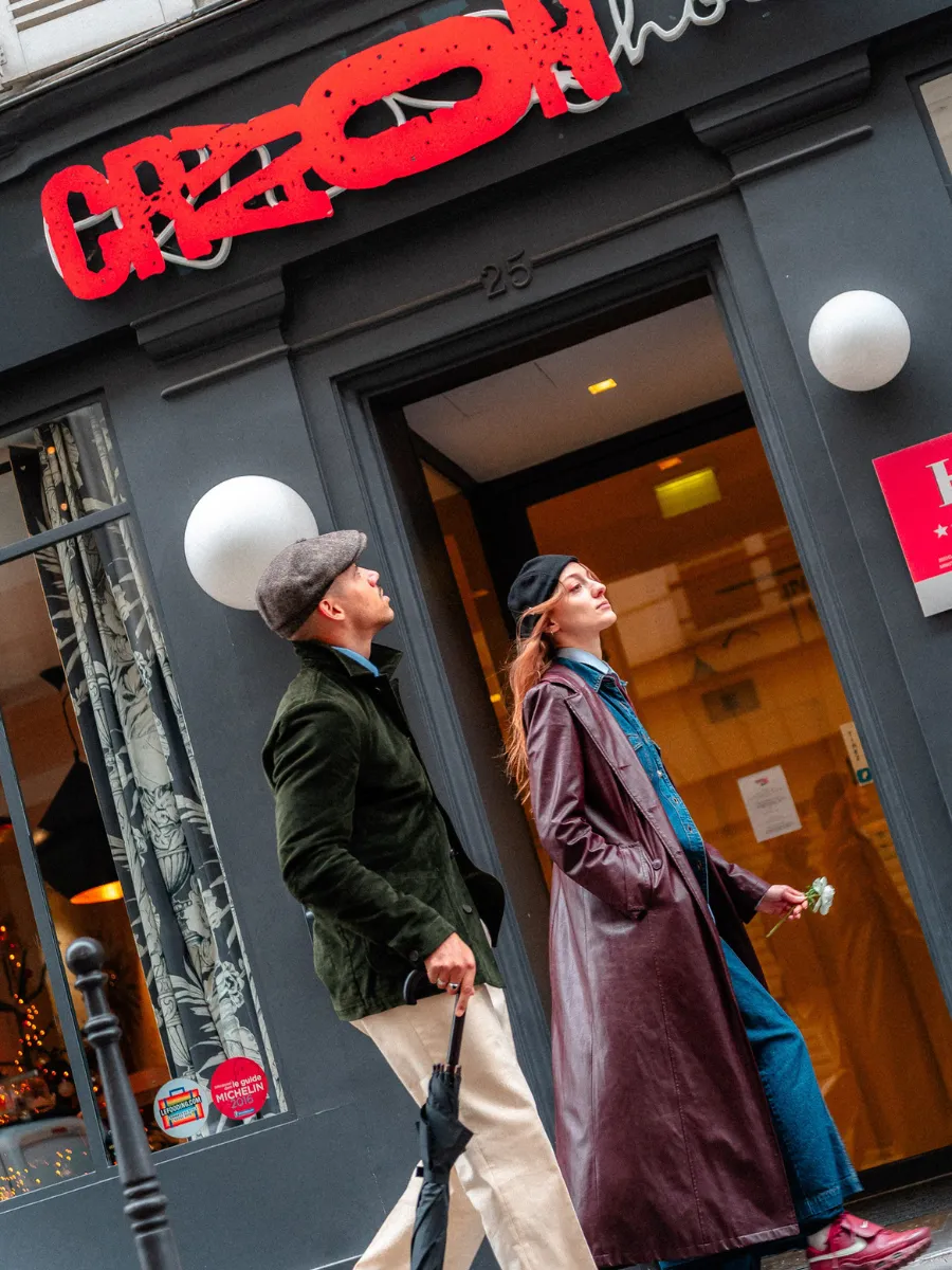 Couple entering the Hôtel Crayon, at 25 rue du Bouloi in Paris's 1st arrondissement, beneath the hotel's red sign