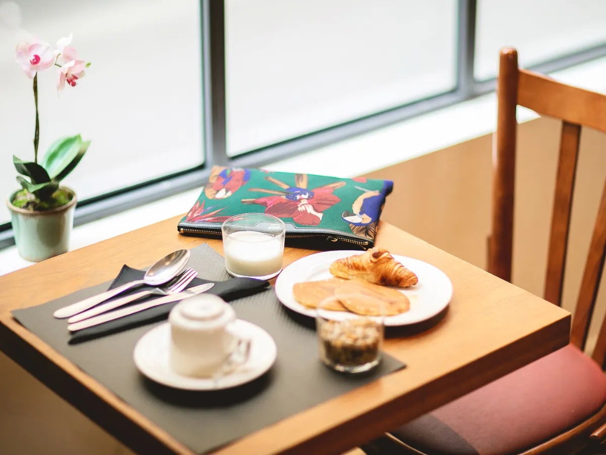 Breakfast table with coffee, crepes, and an orchid by the window at Hôtel Crayon, Paris 1st arrondissement