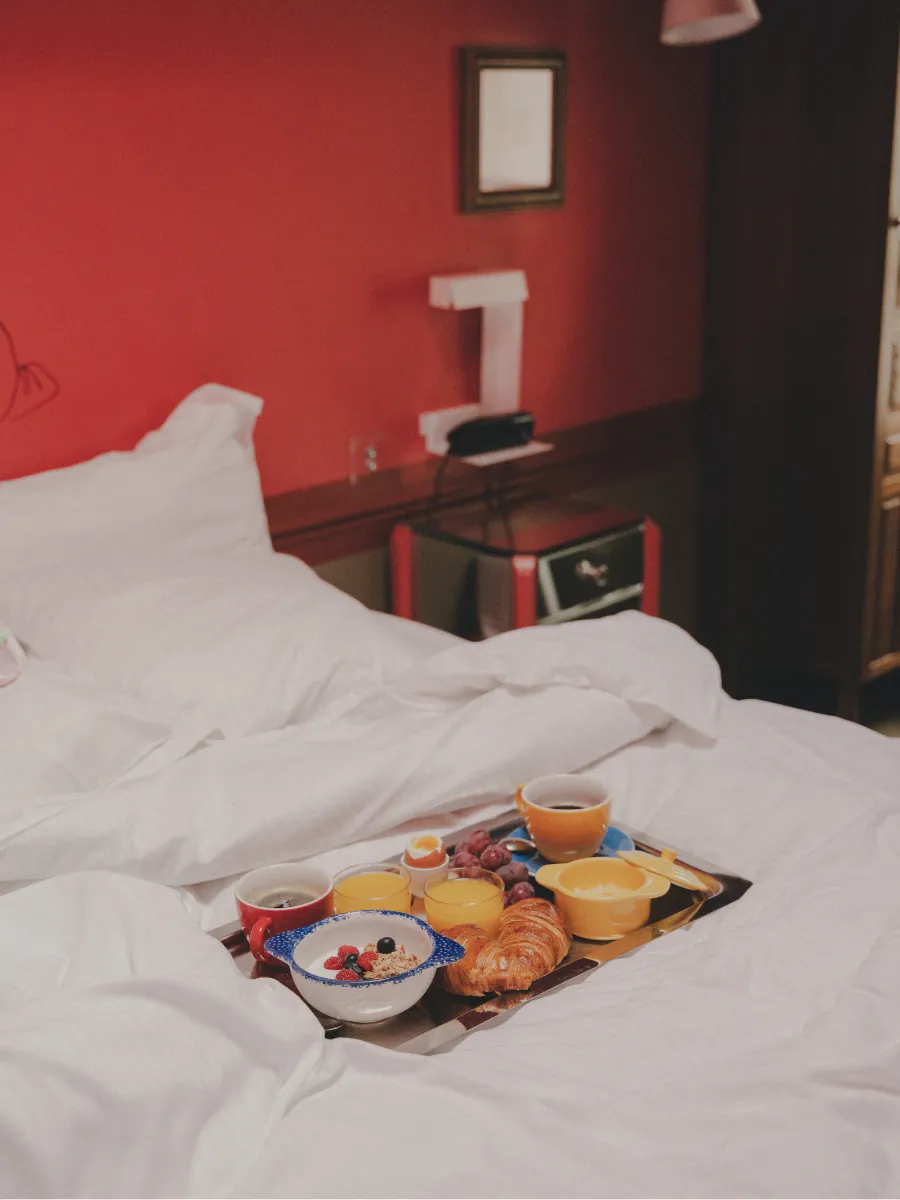 Breakfast served in bed in a red room at the Hôtel Crayon in Paris's 1st arrondissement, near the Louvre