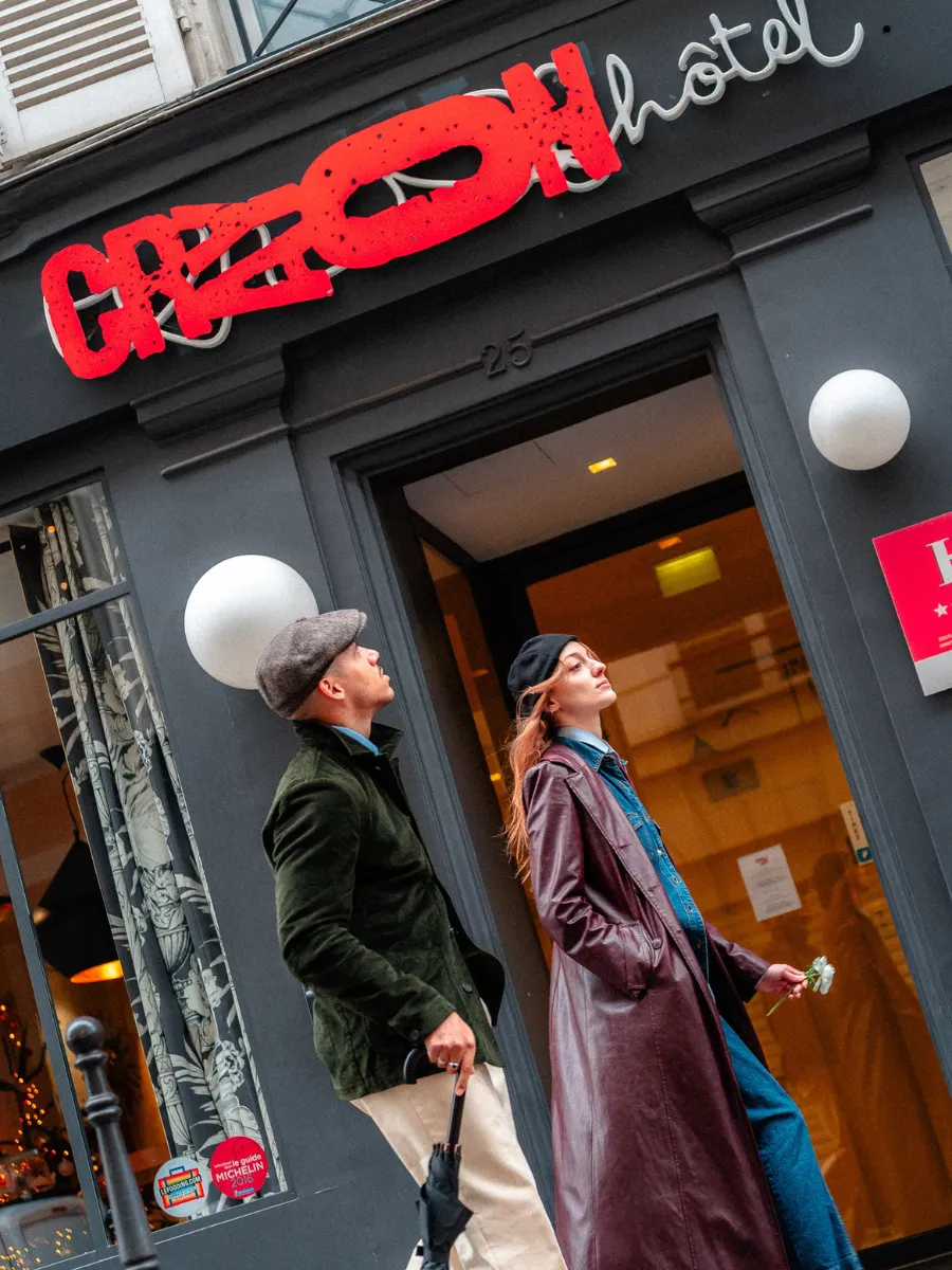 Entrance to the Hôtel Crayon on Rue du Bouloi in Paris's 1st arrondissement, featuring a red sign and a couple walking through the door