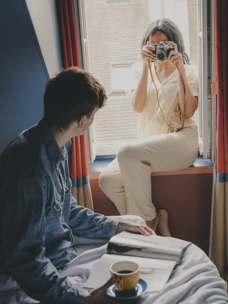 Couple in a room at the Hôtel Crayon in Paris' 1st arrondissement, coffee on the bed and a photo taken from the window