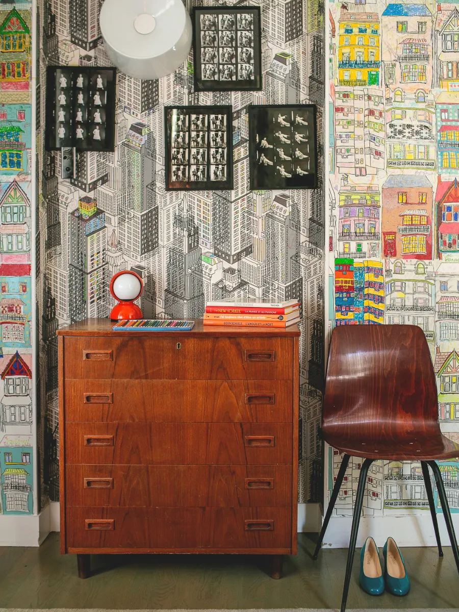 Vintage wooden dresser and red chair in front of a gallery wall in a room at Hôtel Crayon, Paris