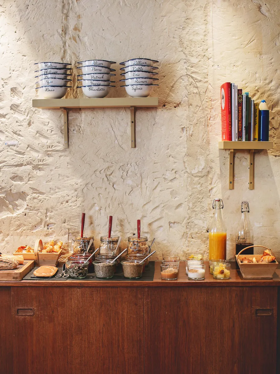 Homemade breakfast buffet on a stone wall with bowls and jams at Hôtel Crayon, Paris 1st arrondissement