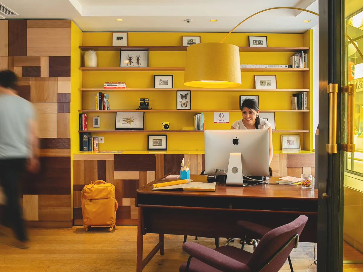 Colorful lobby and reception area at Hôtel Crayon in Paris 1st arrondissement, featuring a yellow bookcase and vintage woodwork