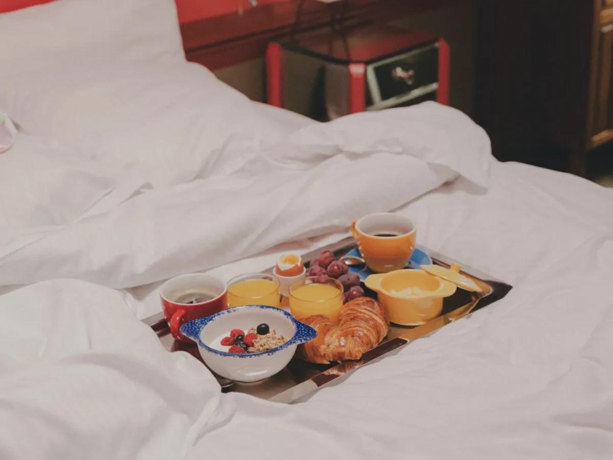 Plateau petit-déjeuner avec croissants, fruits et boissons chaudes sur un lit de l'Hôtel Crayon, Paris 1er