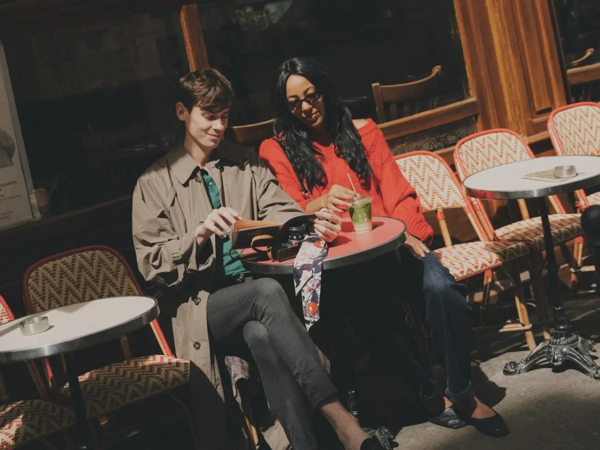 Couple en terrasse d'un café parisien avec chaises en rotin, dans le quartier de l'Hôtel Crayon, Paris 1er