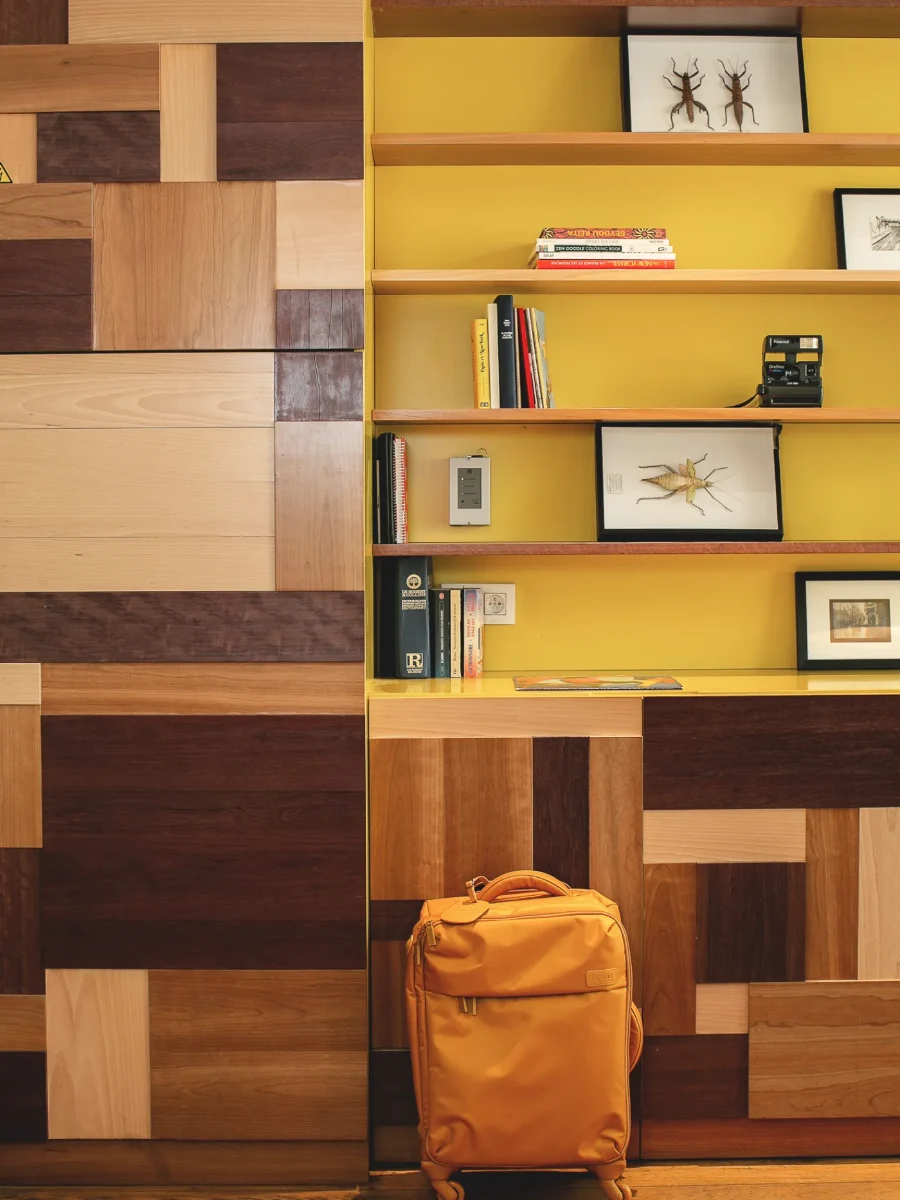 Valise dans le hall de l'Hôtel Crayon à Paris 1er, boiseries patchwork et bibliothèque jaune