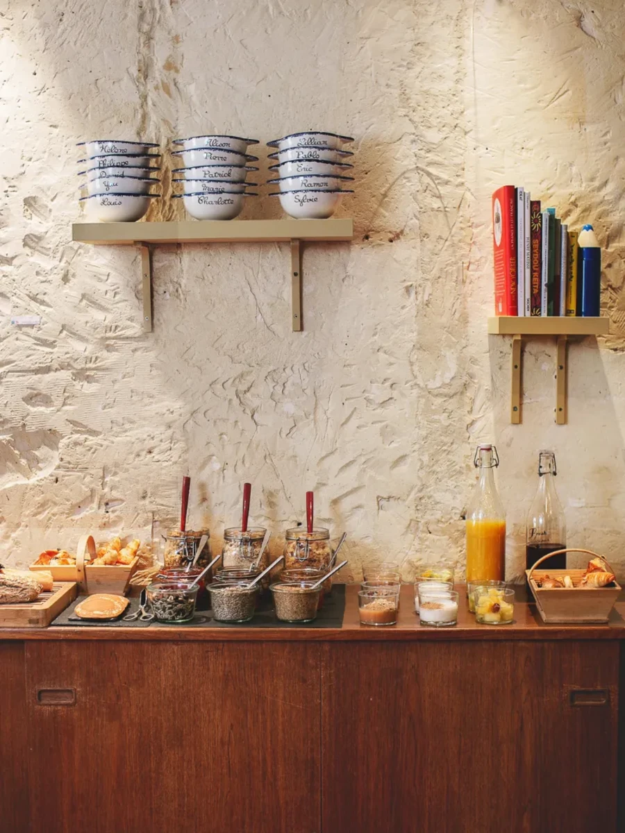 Buffet de petit-déjeuner avec viennoiseries maison et confitures devant un mur de pierre, Hôtel Crayon Paris 1er