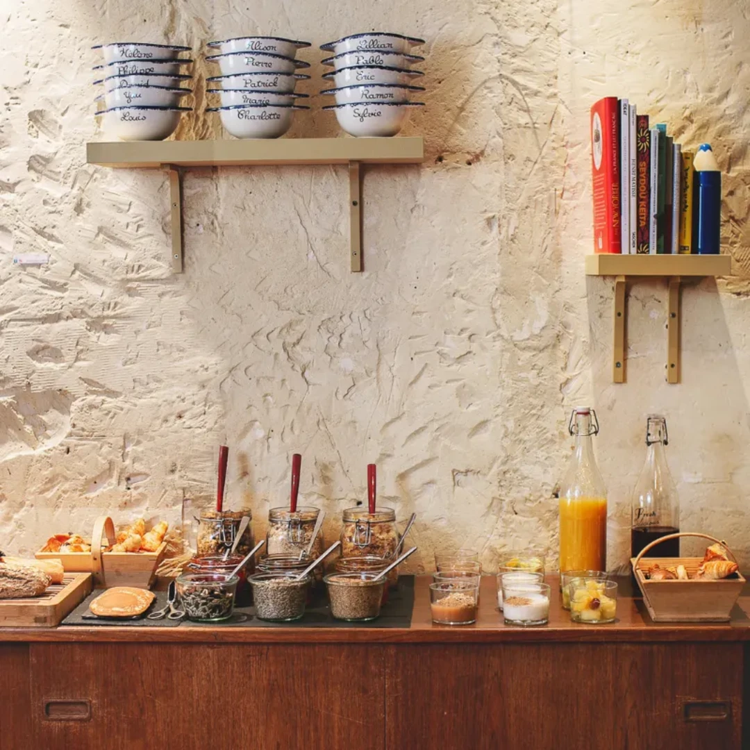 Buffet de petit-déjeuner avec viennoiseries maison et confitures devant un mur de pierre, Hôtel Crayon Paris 1er