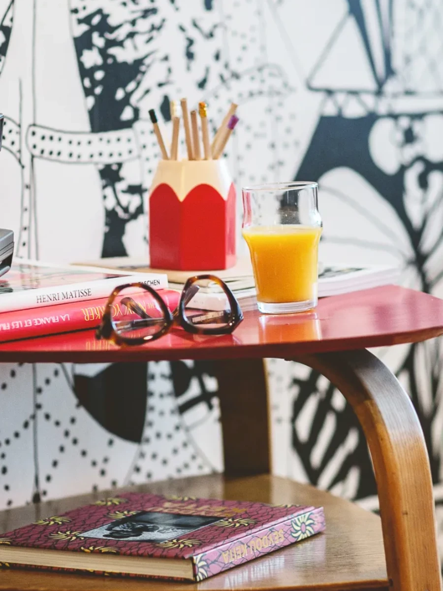 Guéridon rouge vintage avec crayons, lunettes et magazine, avantages et charme de l'Hôtel Crayon à Paris