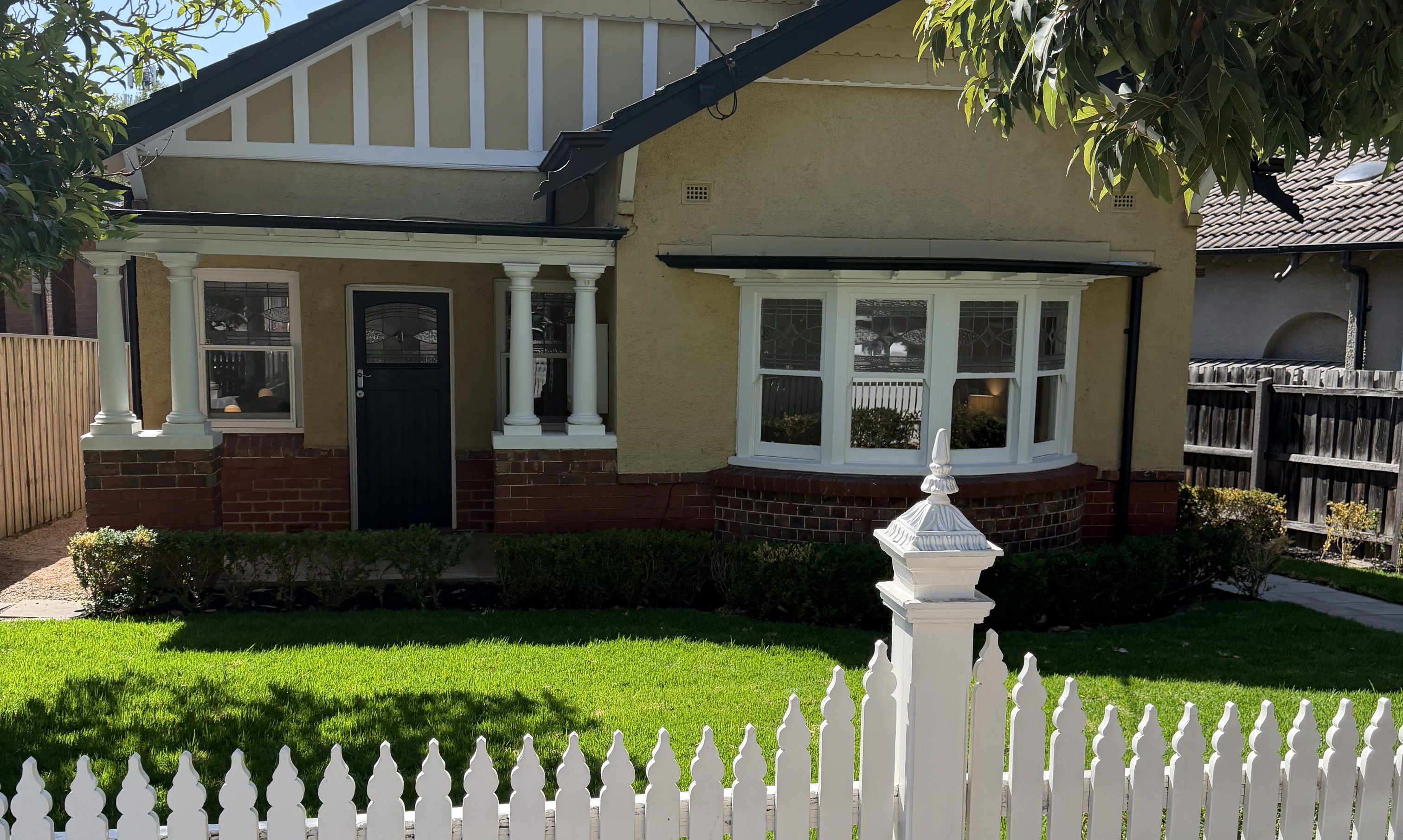 Californian bungalow behind a white picket fence