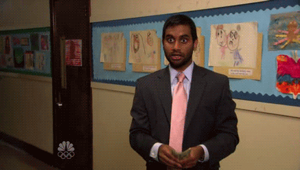 Man in a suit and pink tie counting money with a surprised expression in a hallway with children's drawings on the wall.