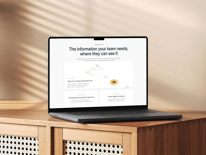 MacBook Air laptop displaying a webpage titled 'The information your team needs, where they can see it' on a wooden cabinet with a beige shadowed background.