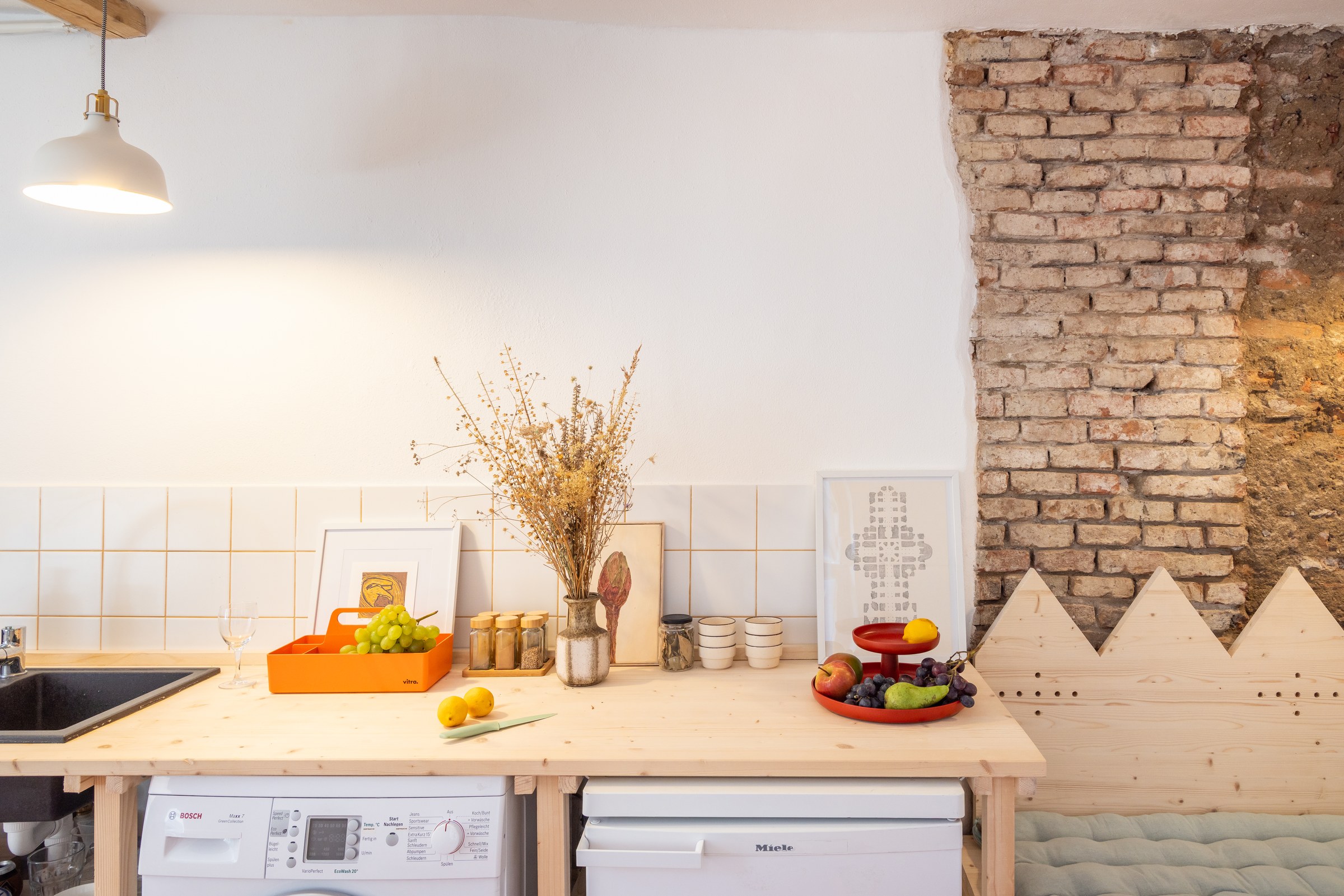 Kitchen with exposed brickwork, pendant lighting and colourful accessories