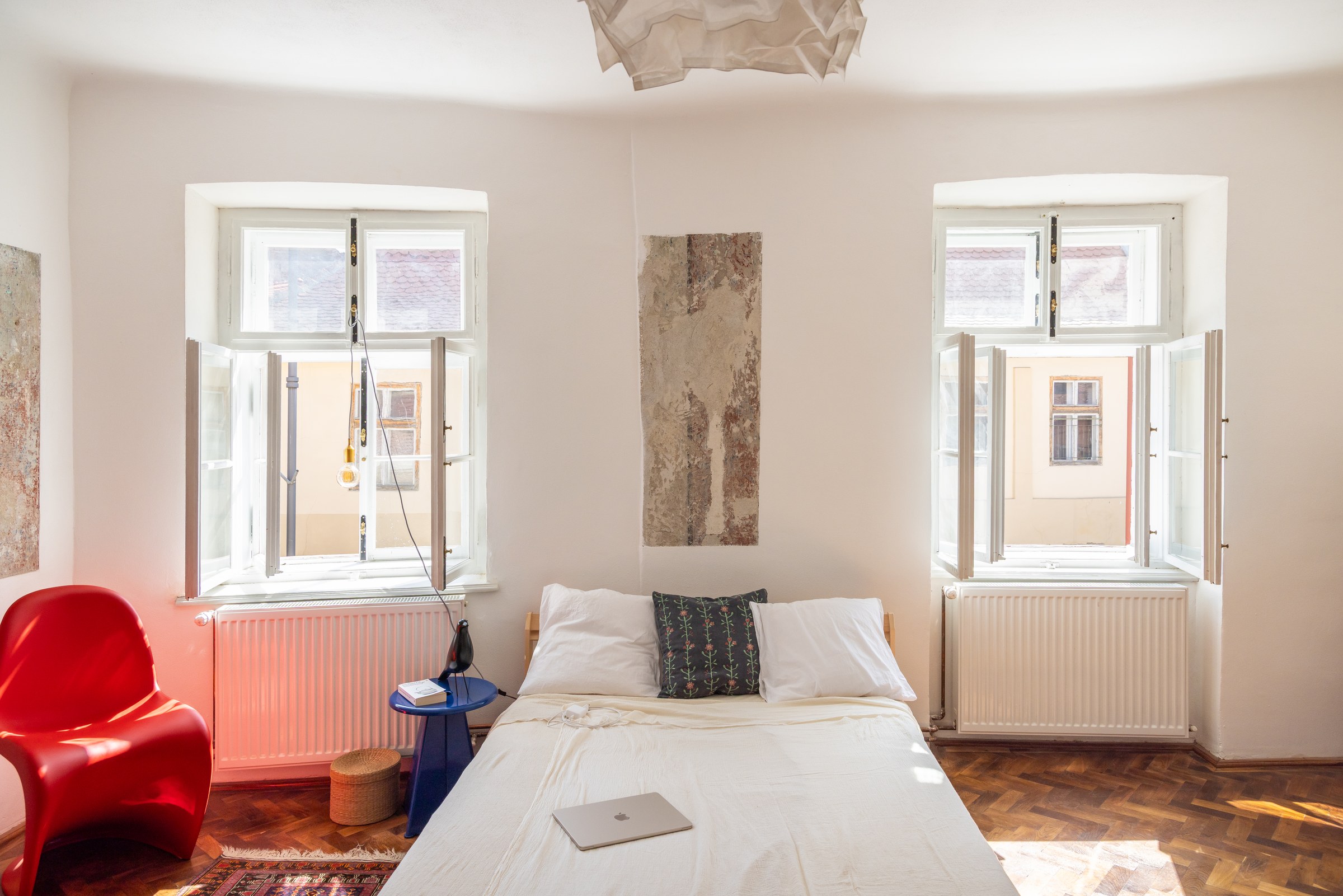 Bedroom with a red Vitra Panton chair and blue side table in a Sibiu apartment