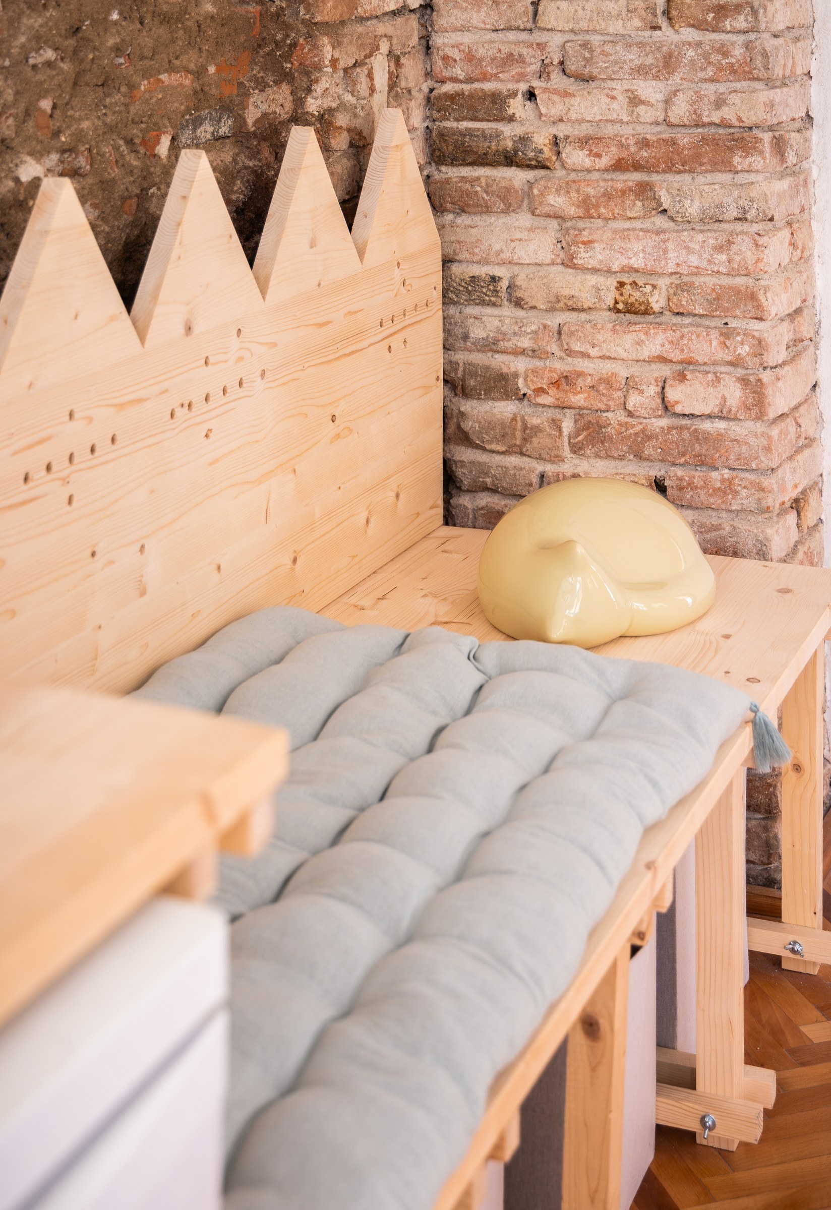 Cushioned seating and a pale yellow stool beside exposed brickwork