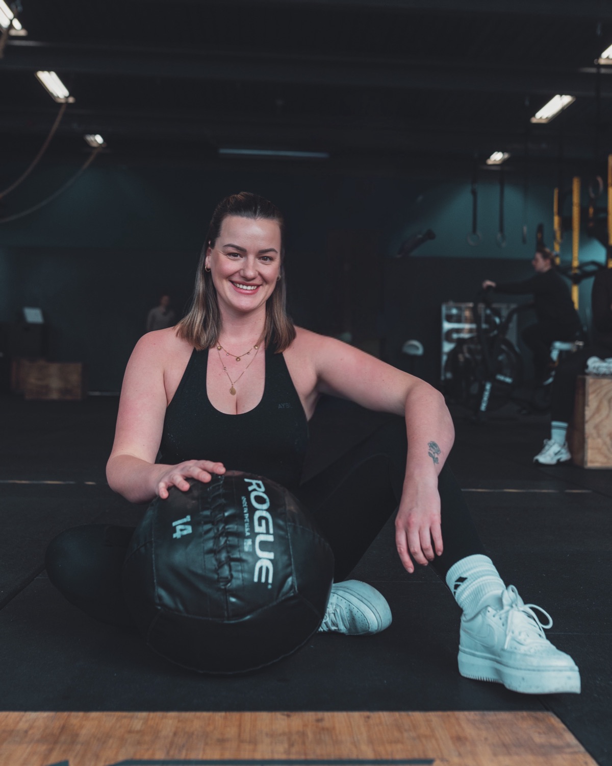 Laura, Gründerin von mamamoves, sitzt lächelnd mit Medizinball im Studio