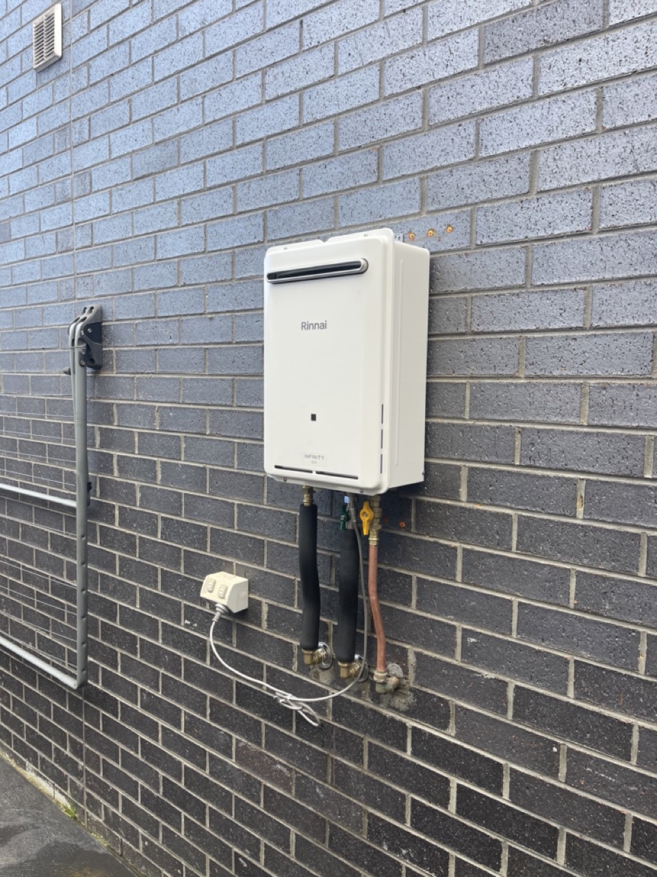 New Rinnai gas hot water system installed on brick wall