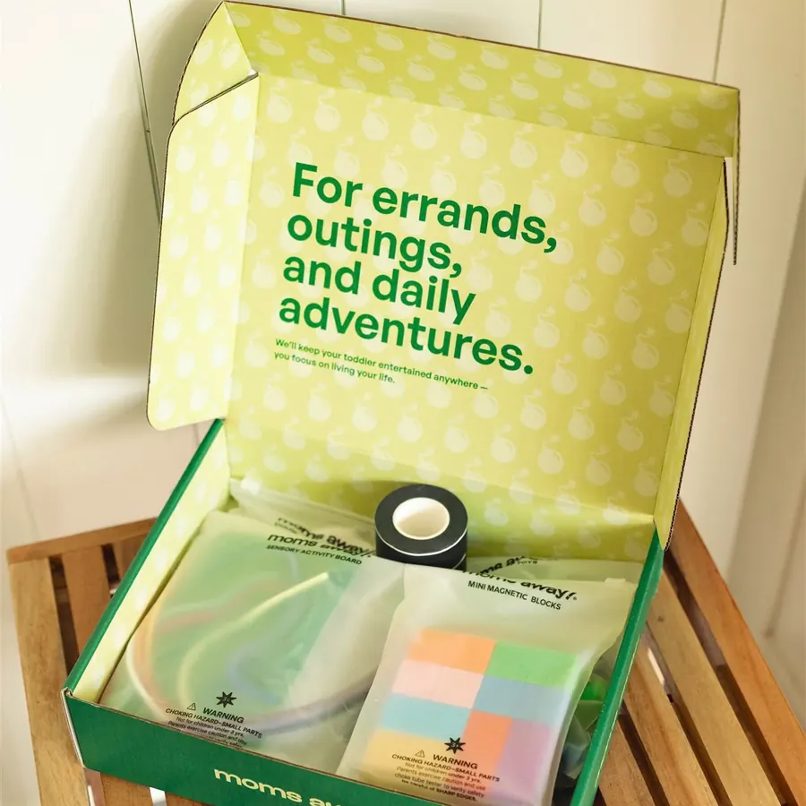 An open Moms Away activity kit box with pouches inside
