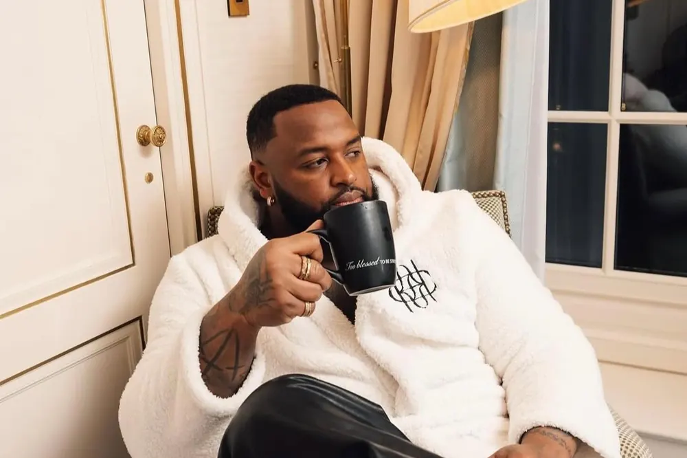A man in a white Chasa robe holding a branded mug