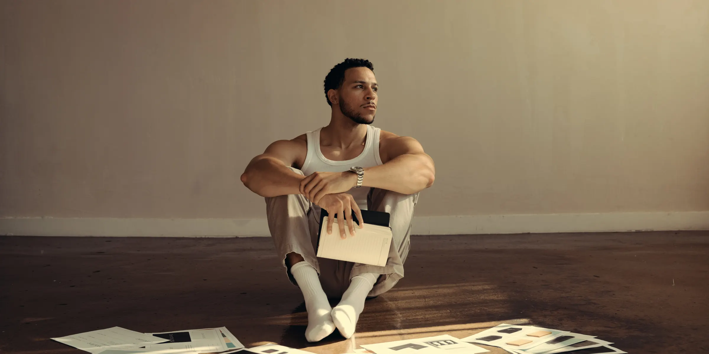 A creator sitting on the floor surrounded by printed photographs and artwork